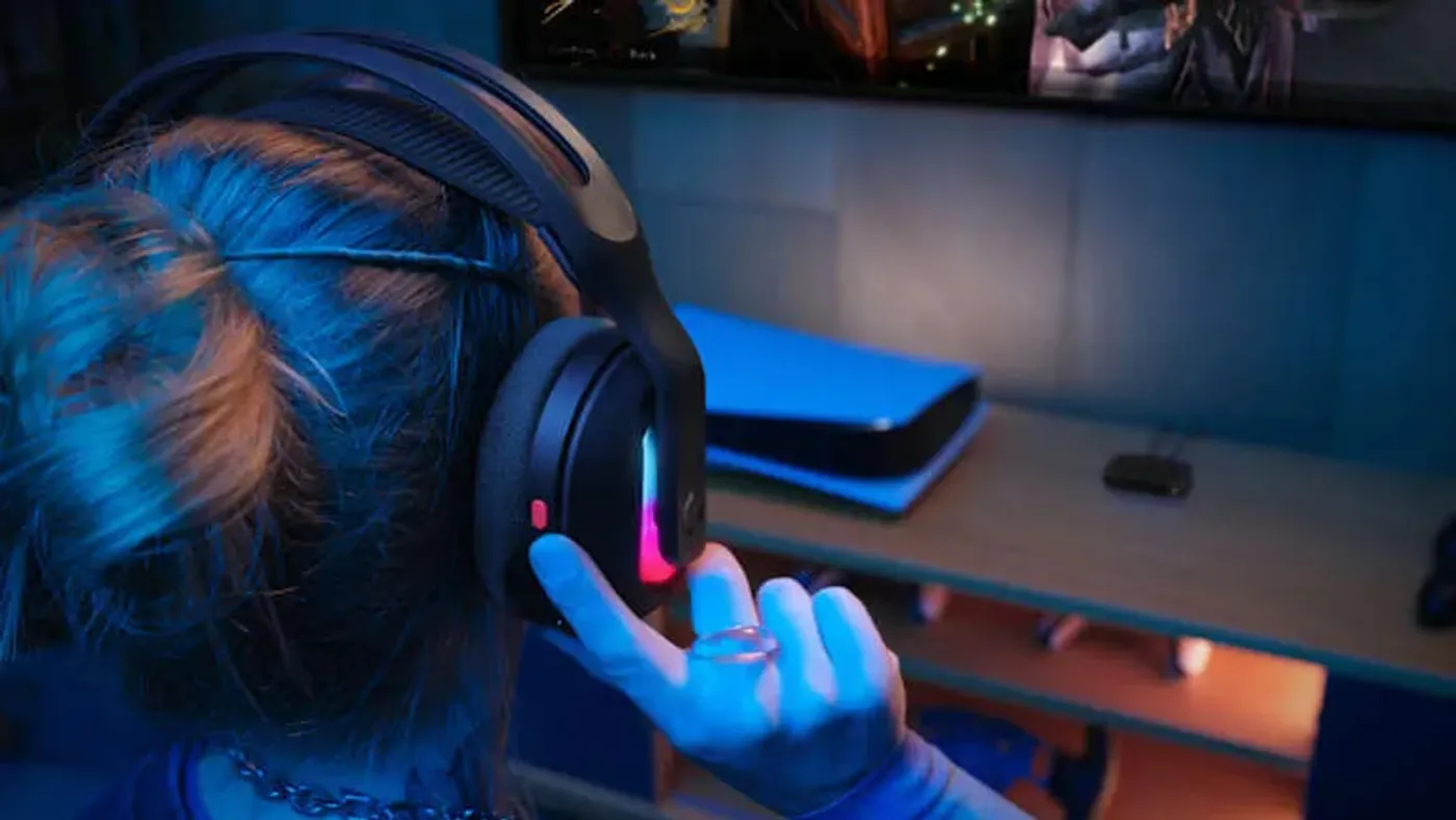 Gamer using Astro A20 X headset with PLAYSYNC dual-system switching capability