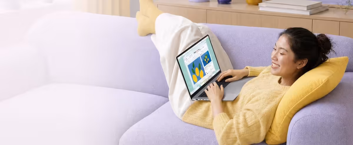 A person reclines on a sofa using the ASUS Vivobook 16 in a bright living room.