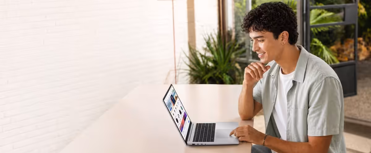 A person sits at a table using the ASUS Vivobook 16 in a bright indoor setting.
