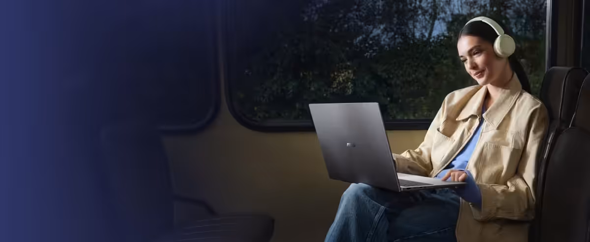 A woman using a light blue ASUS Vivobook S14 while commuting on a bus.