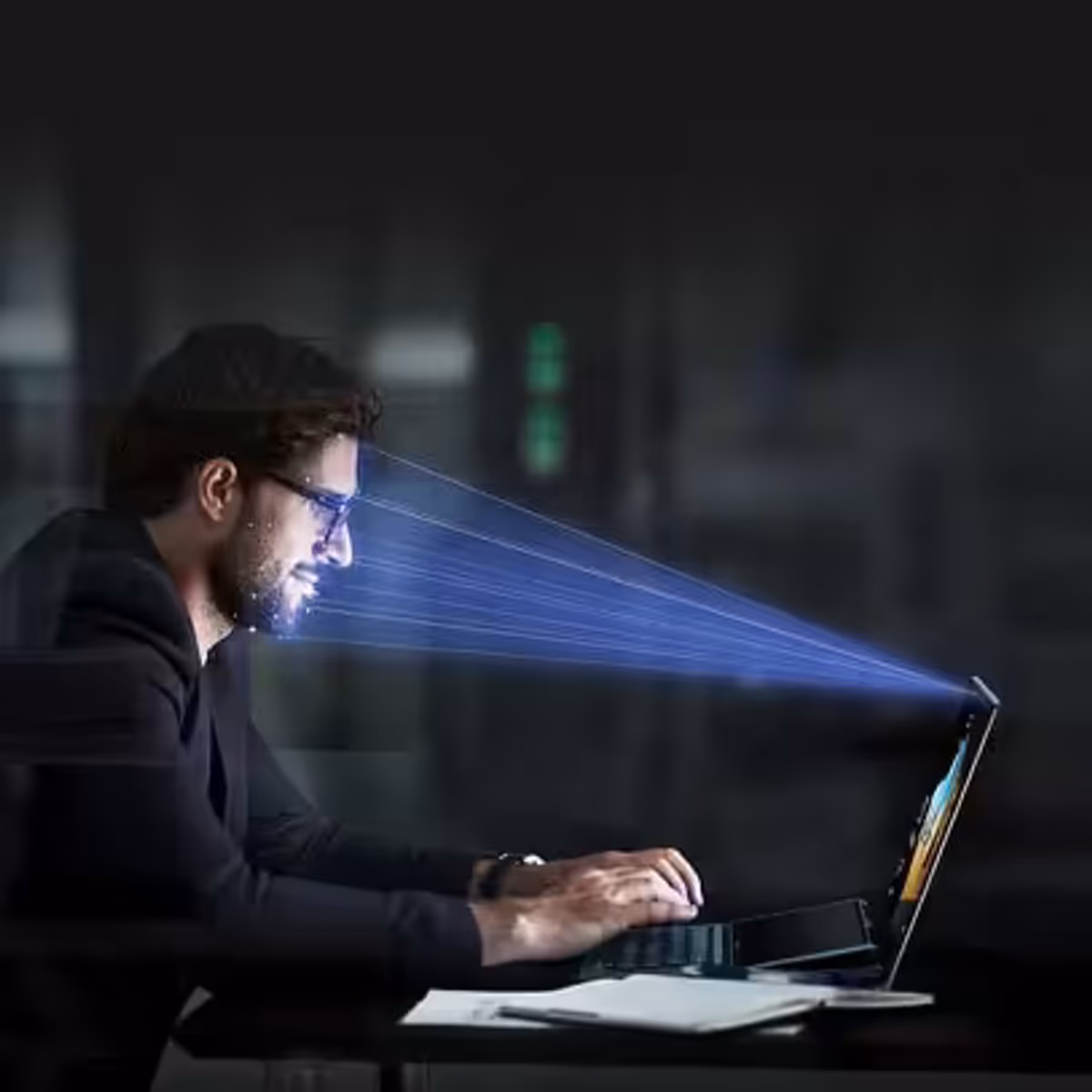 A beam of light is projected onto a man’s face indicating that his face is being scanned by the laptop IR camera.