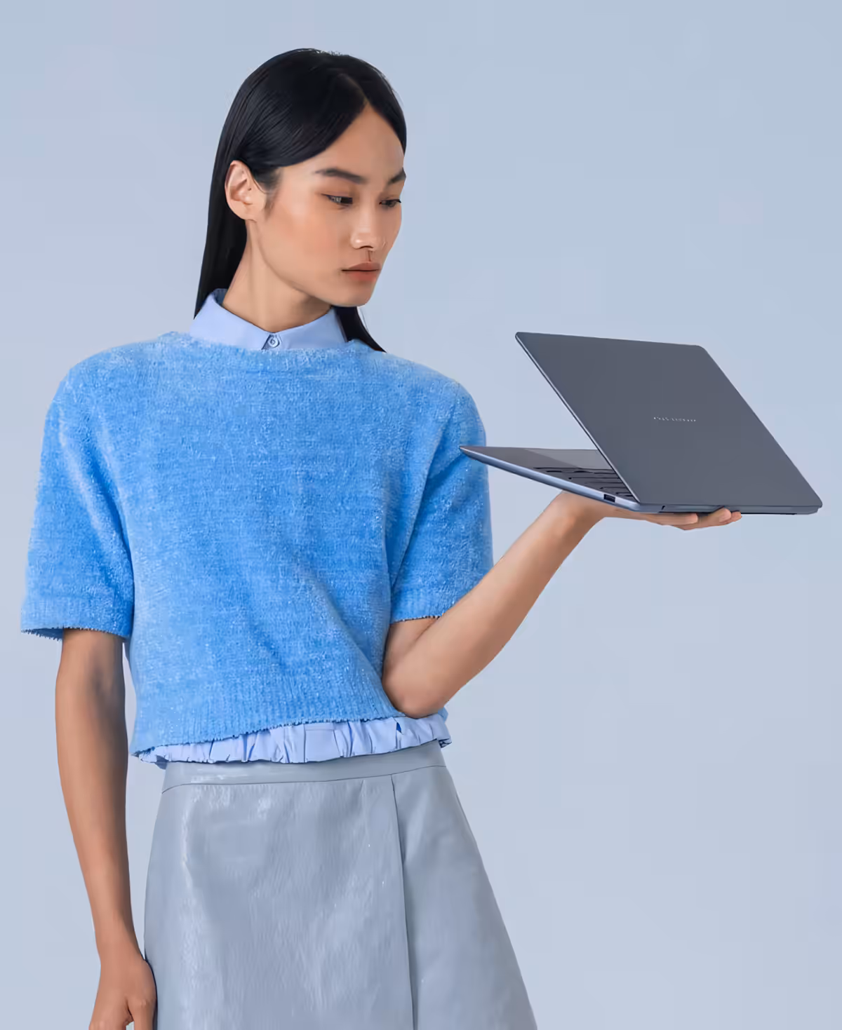 Person holding slim Arctic Blue ASUS Zenbook 14 laptop in modern setting