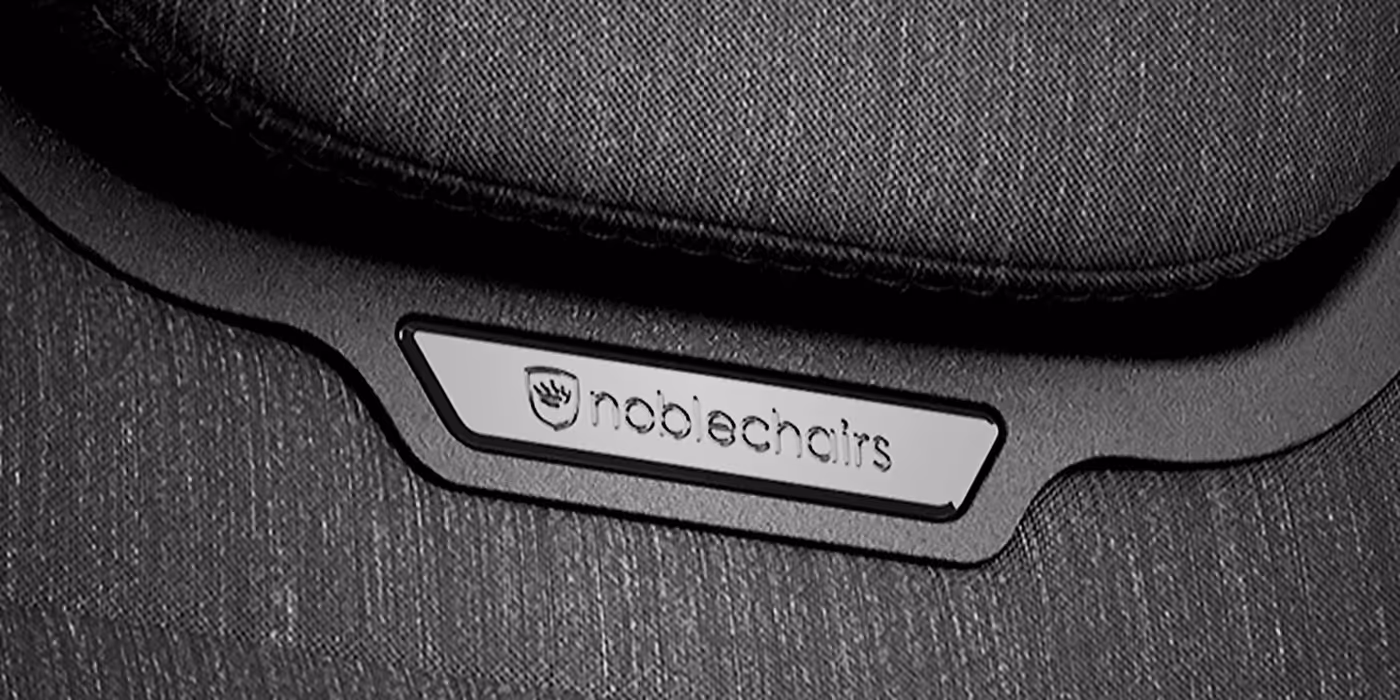 Close-up of the magnetic metal emblem on the AURA TX chair frame