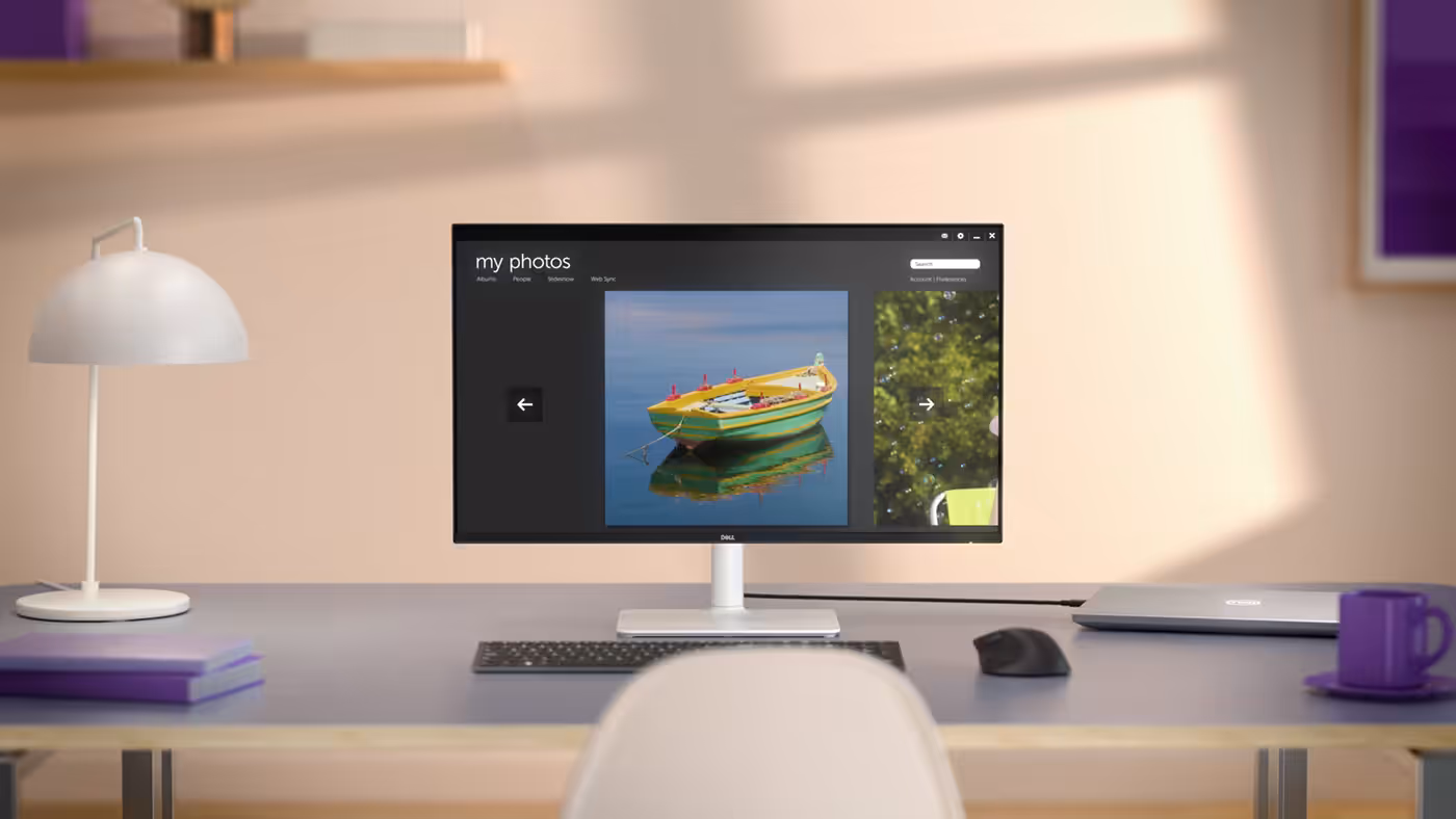 A desk setup featuring family using a Dell 32 Plus Monitor with a laptop, keyboard and mouse connected.