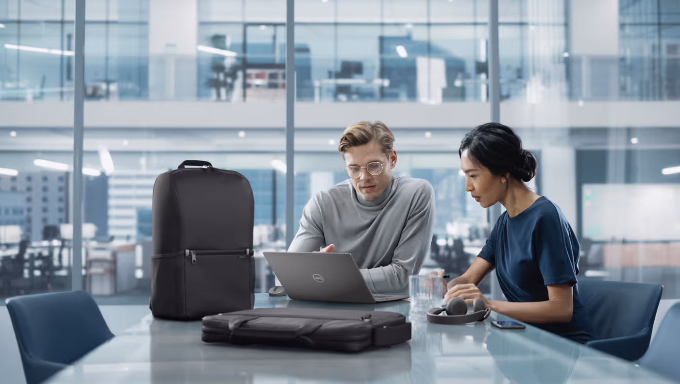 Man and woman at an office table using a laptop with Dell EcoLoop products nearby