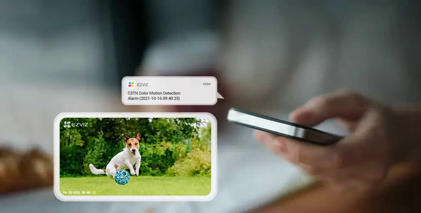 Smartphone running the EZVIZ app showing a live camera feed and motion alert