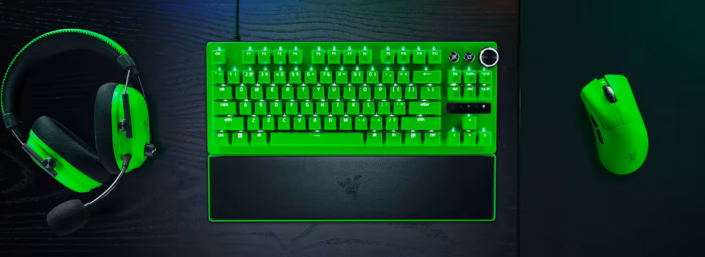 Green-lit gaming headset, keyboard, and mouse on a black desk glowing bright green.