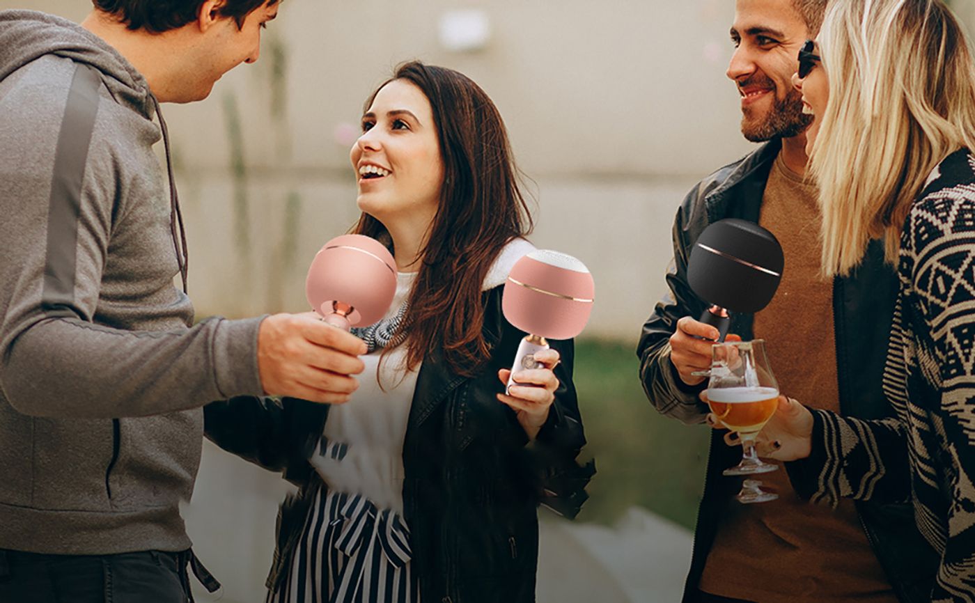 Friends gathered around using the Monster M97 Superstar karaoke microphone