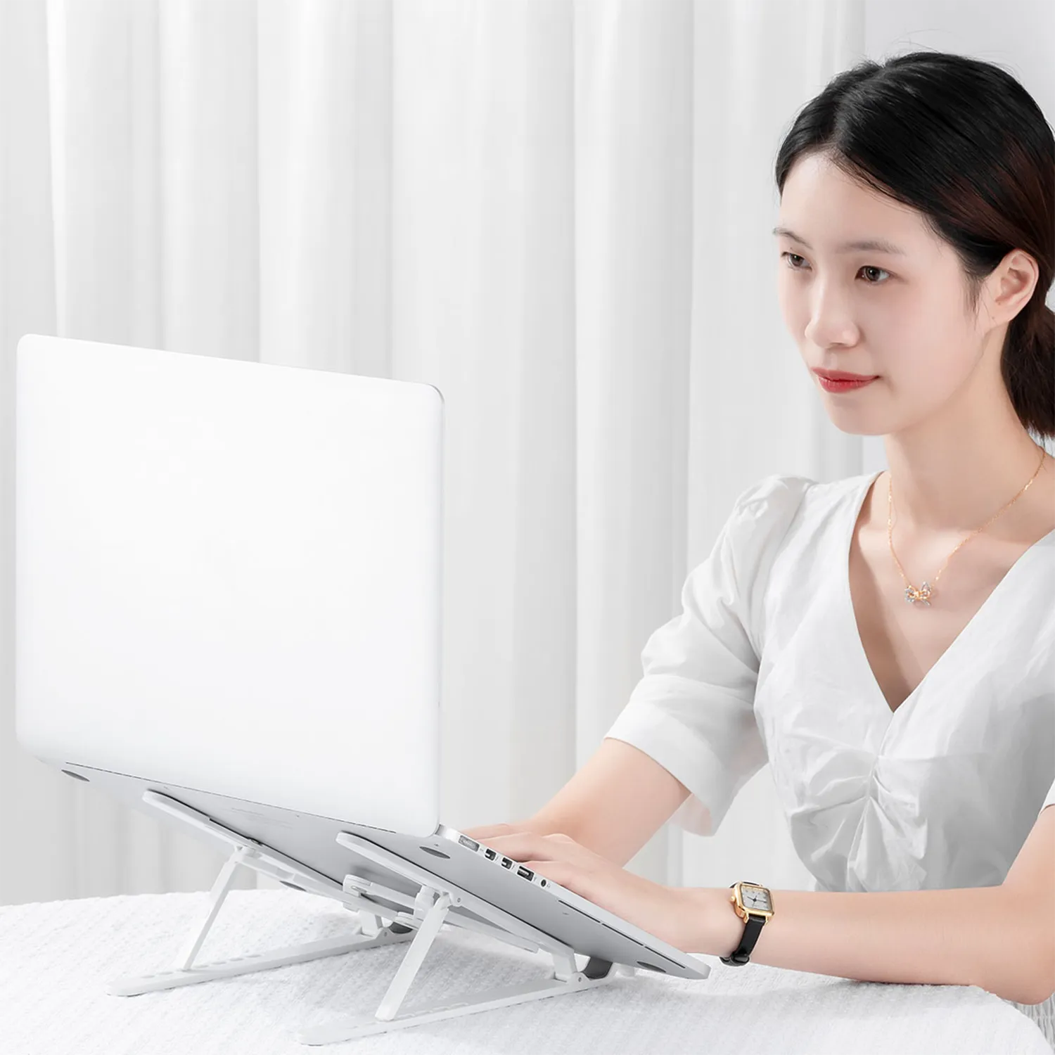 User typing on laptop mounted on ORICO stand