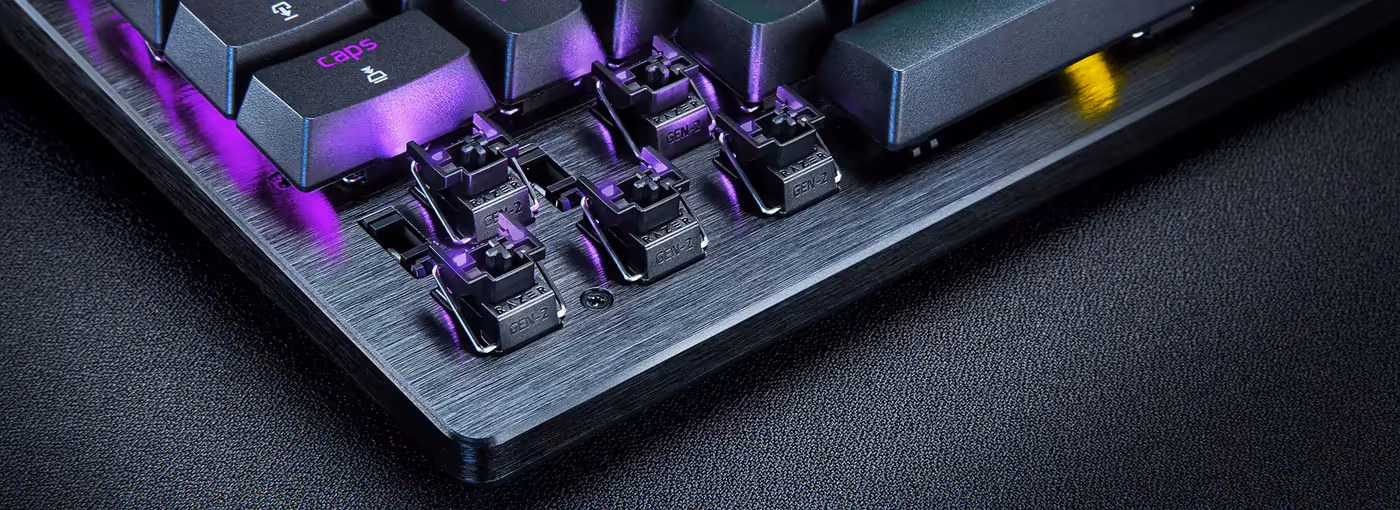 Close-up of a mechanical keyboard with visible switches and keycaps, emitting purple LED lighting over a brushed metal base.