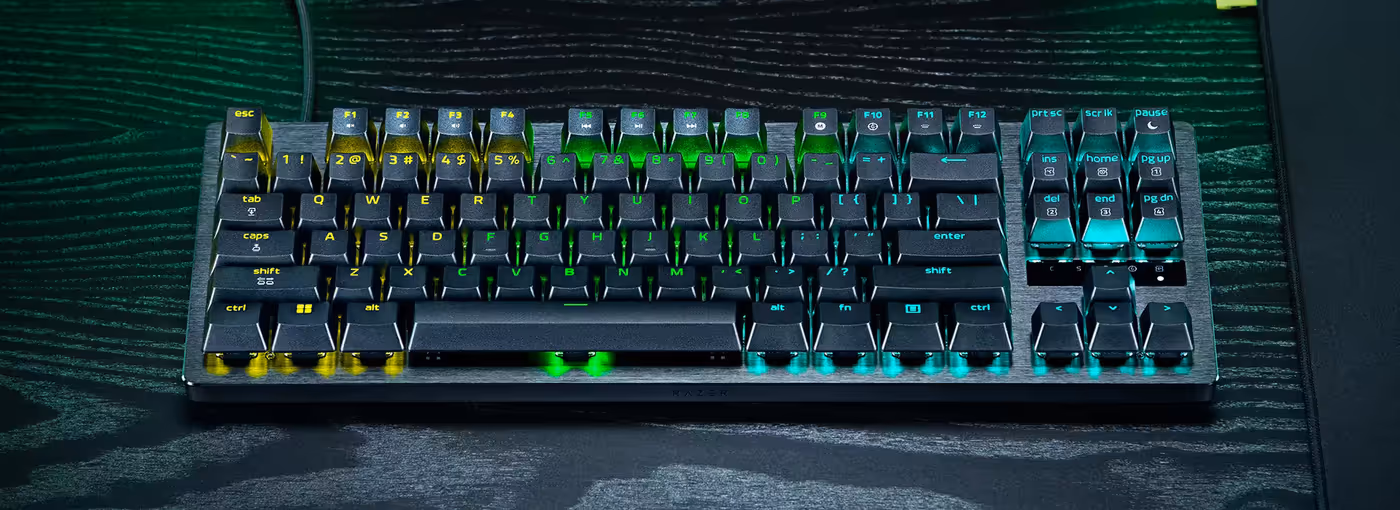 Razer mechanical keyboard with RGB backlighting, black keys with yellow, green, and turquoise accents on a black textured surface.