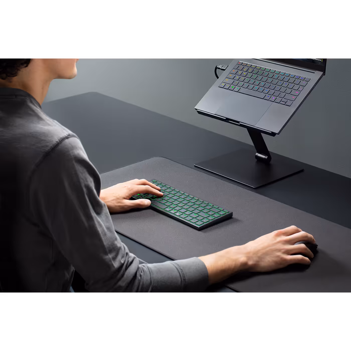 Person typing on the Razer Joro at a desk with a laptop on a stand