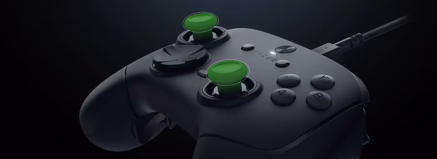 A close-up of a Razer gaming controller highlighting dual analog sticks with green accents, buttons, and a wired connection.