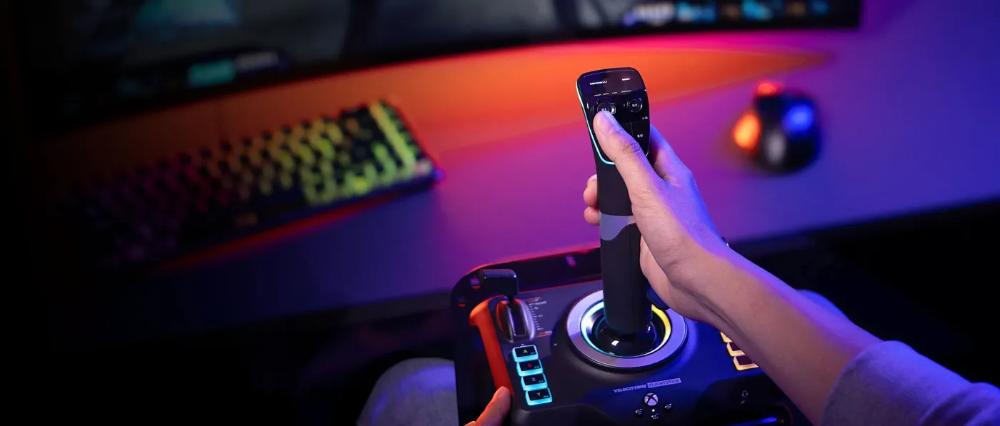 Gaming joystick with colorful buttons against illuminated keyboard and monitor setup