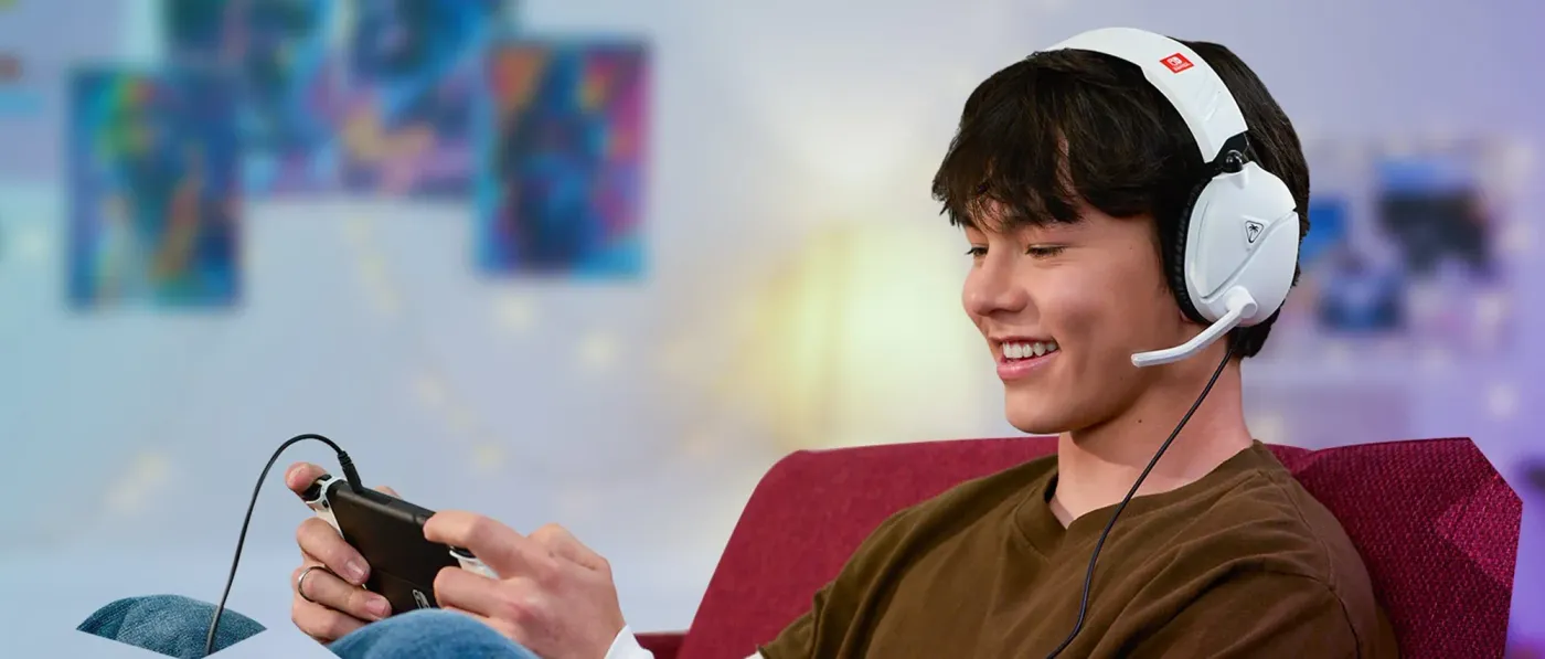 Young person smiling while playing a handheld Nintendo Switch gaming console on a couch