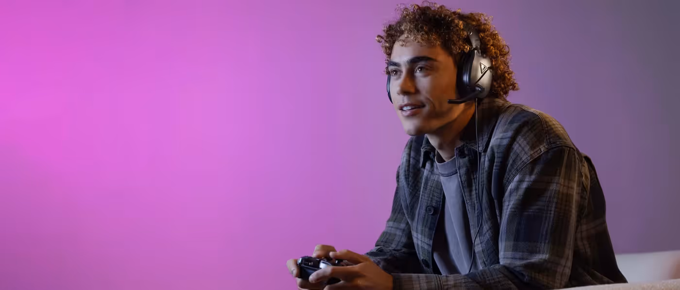 Young person gaming with controller and headset against a purple background