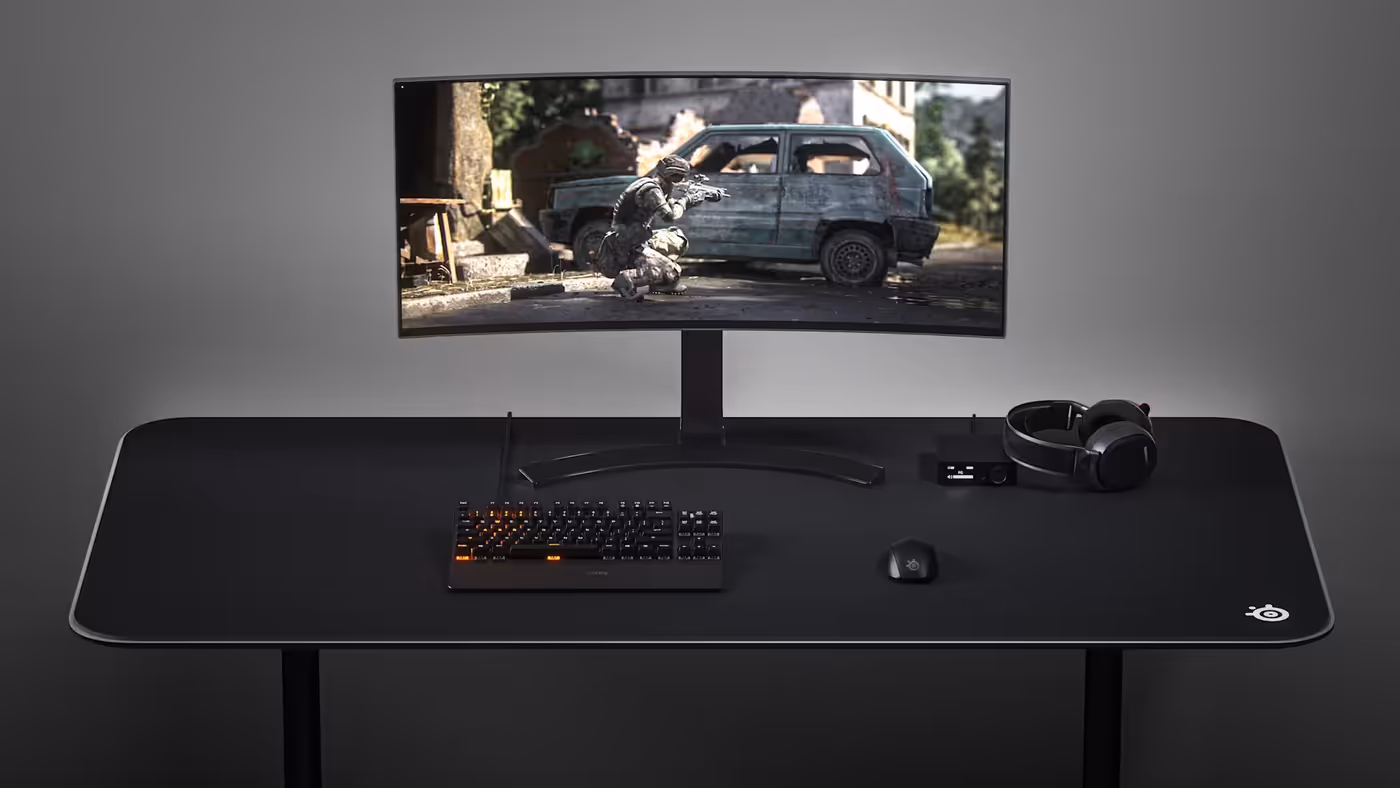 The entire SteelSeries set, keyboard, mouse, mouse pad, and headphones on the desk.