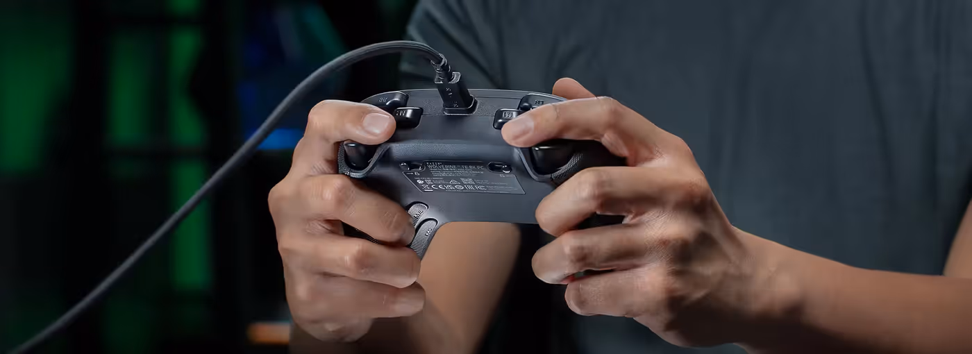 Close-up of hands holding the controller focusing on the detachable braided connection cable.