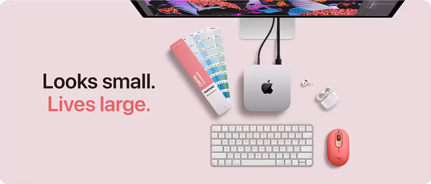 Mac mini on a desk beneath a display, with keyboard and mouse
