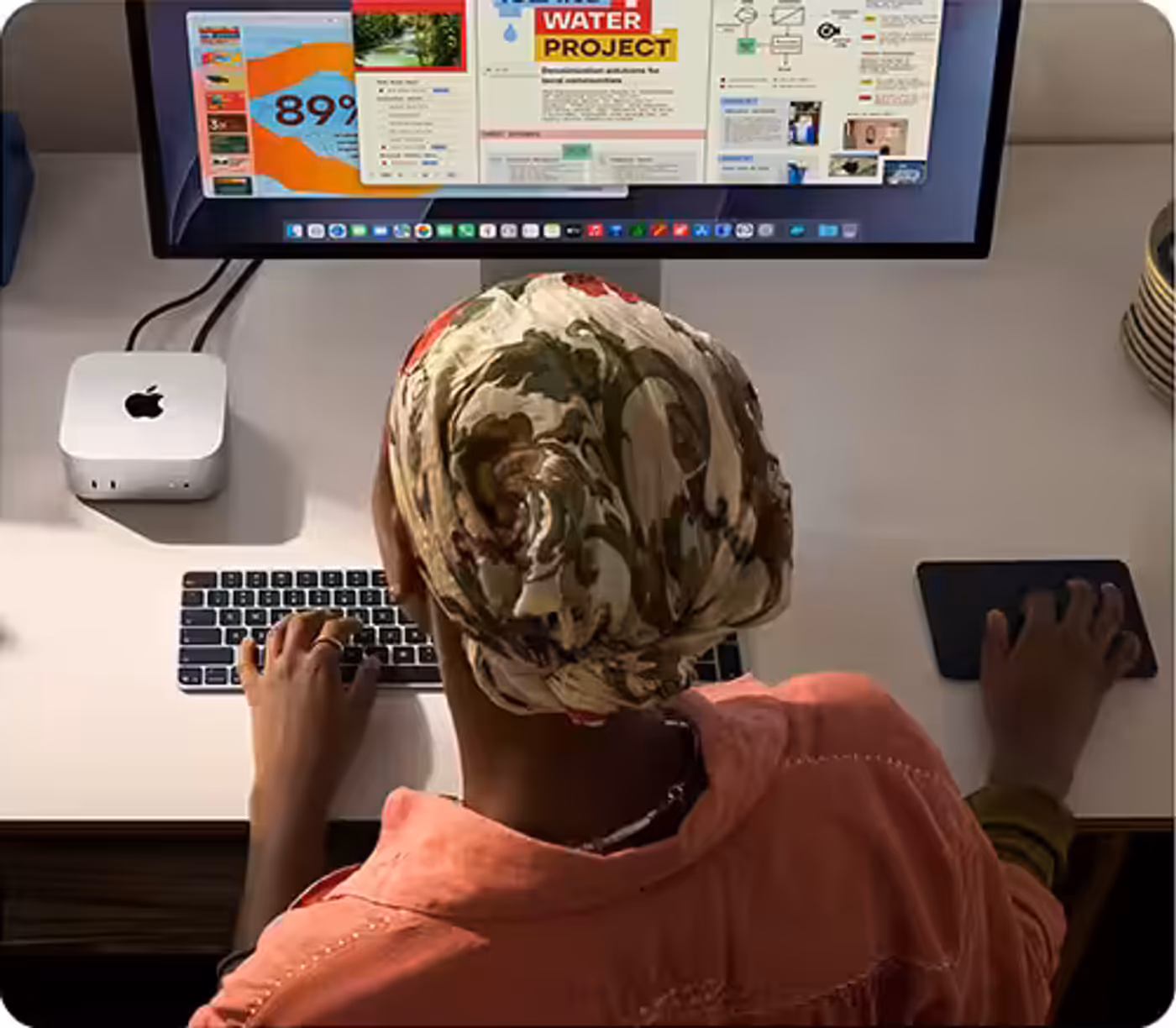 Person working at a desk with a Mac mini and a display